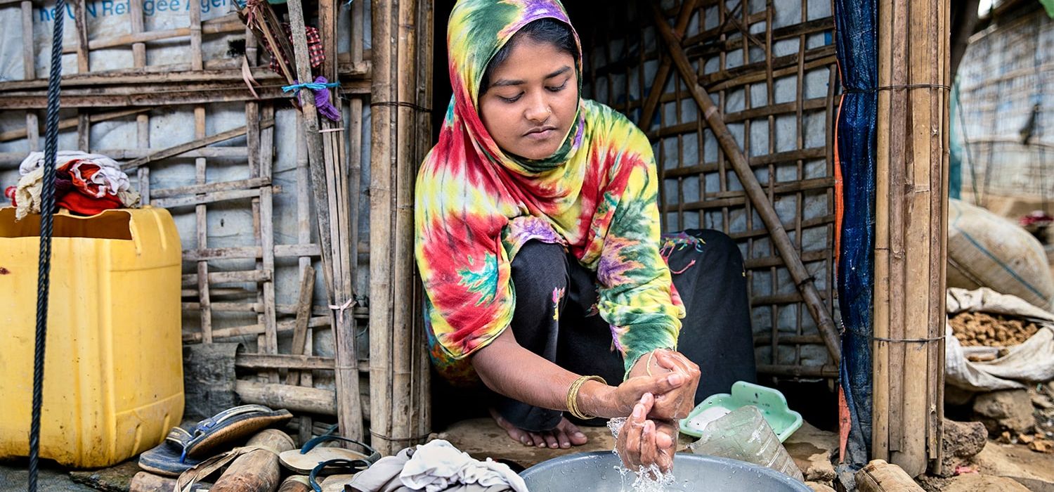 A girl outside washing her hands.